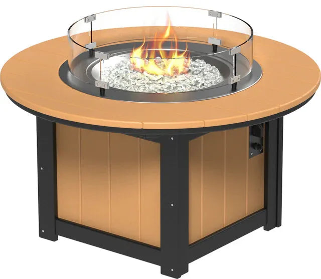 A LuxCraft Lumin 46" Cedar Round Fire Pit with a glass wind guard and a fire burning, showcasing white fire glass within