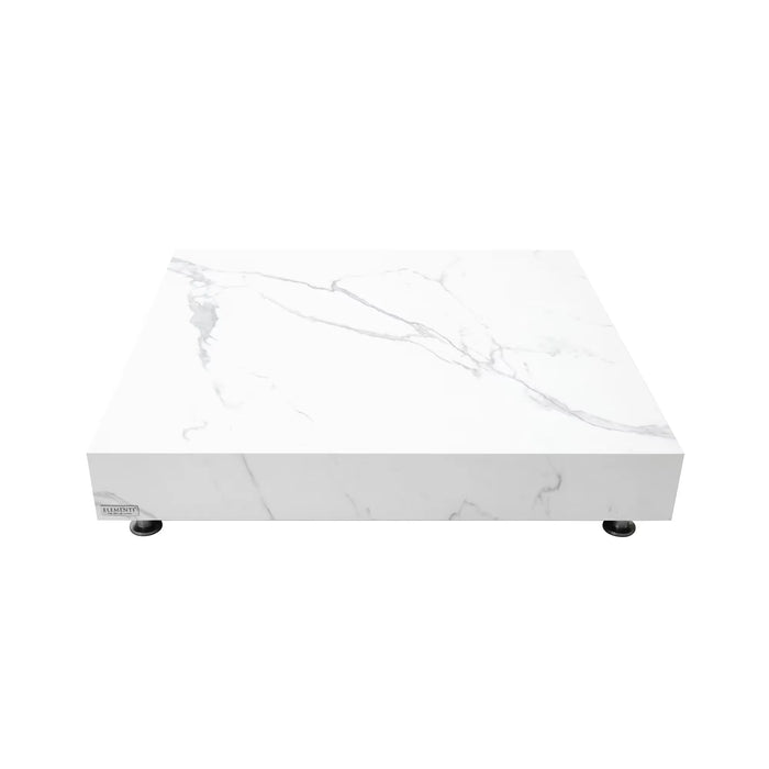 A low, square coffee table with a white marble top and base, resting on small, dark, round feet.