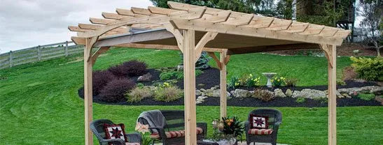 A light-colored wooden pergola with a fabric canopy partially extended, providing shade over a patio area with chairs and a small table.