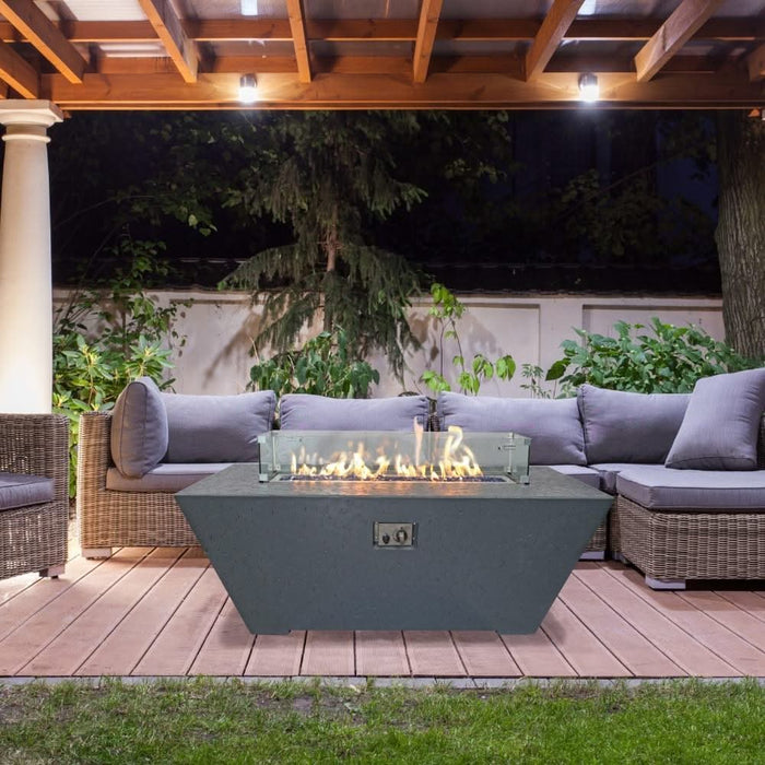 grey rectangular fire pit with rectangle glass wind suard over flame. fire pit has start stop ignition button on side and is placed in front of patio furniture under a gazebo