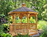 A wooden octagonal gazebo with a shingled roof and a decorative cupola. The gazebo features latticework detailing on the walls, a spacious interior with a brick floor, and a wooden bench.