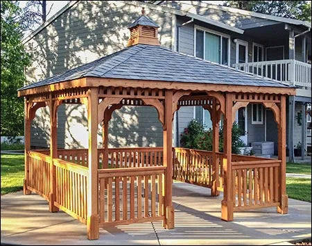 A large, cedar rectangle gazebo with a gray roof and cedar walls. The gazebo has a decorative cupola at the top and is surrounded by a wooden railing.