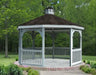 A gray octagonal gazebo with a classic design stands on a brick patio surrounded by greenery. The gazebo features a shingled roof with a cupola, decorative railings, and built-in benches. Trees and shrubs frame the gazebo in the background.