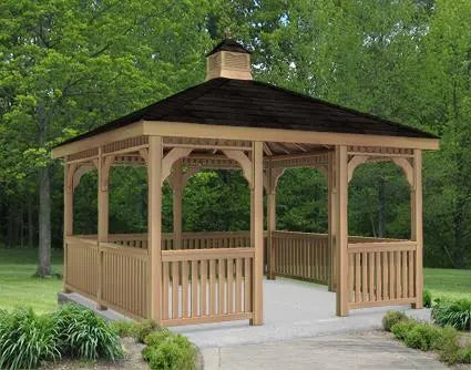 A large, square cedar gazebo with a double roof and decorative cupola. The gazebo features intricate latticework details, a spacious interior, and a surrounding picket fence.