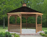 A large octagonal wooden gazebo with a shingled roof and a decorative cupola. The gazebo features a spacious interior with open latticework walls and is surrounded by a brick patio and lush greenery.