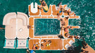People enjoying a pool party on a floating platform in the middle of a body of water.