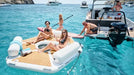 People enjoying a day on a yacht with inflatable loungers and water toys.