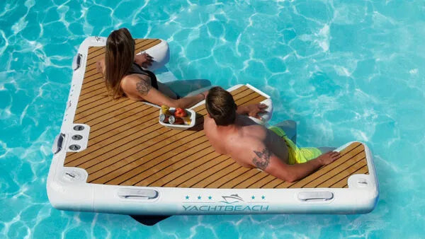 Two people relaxing on a YachtBeach inflatable platform in a pool.