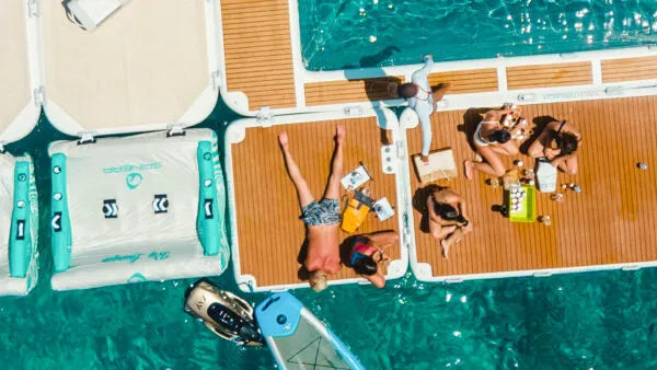 People relaxing on a floating dock with turquoise water below