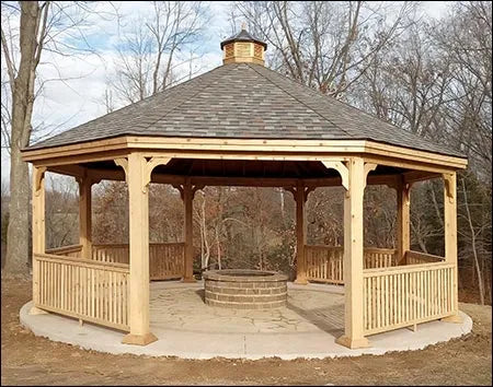 A large octagonal wooden gazebo with a shingled roof, decorative cupola, and lattice railings. A brick fire pit is centered in the gazebo's floor.