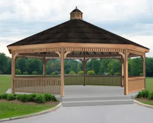 A large, wooden dodecagon gazebo with a shingled roof and a decorative cupola. The gazebo features a spacious interior with open latticework walls, a surrounding deck, and steps leading up to the entrance.