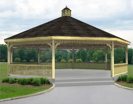 A large dodecagon gazebo with a classic design. It features a shingled roof with a decorative cupola, and intricate latticework railings surrounding the open structure. The gazebo is painted a light brown color, with a raised floor and steps leading up to it. There is a decorative band around the base of the gazebo.