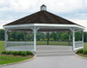 A large octagonal gazebo with a classic design. It features a shingled roof with a decorative cupola, and white latticework railings surrounding the open structure. The gazebo has a raised floor with steps leading up to it.