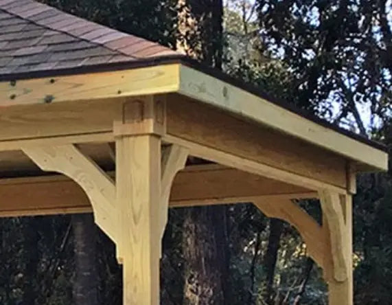 Close-up of a wooden gazebo roof overhang with decorative brackets and a dark-colored roof.