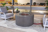  Fire Table in gray with lava rocks and glass wind guard, surrounded by gray armchairs and a built-in seating area in a contemporary indoor space.