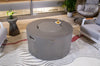 43inch-round-fire-pit-table-light-grey-elementi-pacaya" showing an image of the fire pit with a lid, set in a patio-like setting with chairs and a side table.