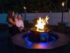 couple enjoying a drink sitting down on a chair in front of a fire pit with water feature 