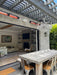 Modern outdoor living space with dining table and chairs, open to a living room and patio  heater