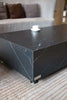 A rectangular black marble porcelain coffee table with cups on it in a living room setting.