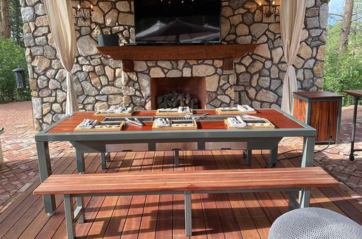 Outdoor stone fireplace with an outdoor korean bbq grill table and bench on a wooden deck