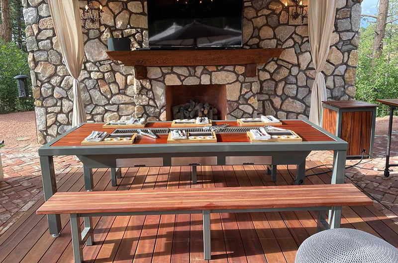 Outdoor stone fireplace with an outdoor korean bbq grill table and bench on a wooden deck