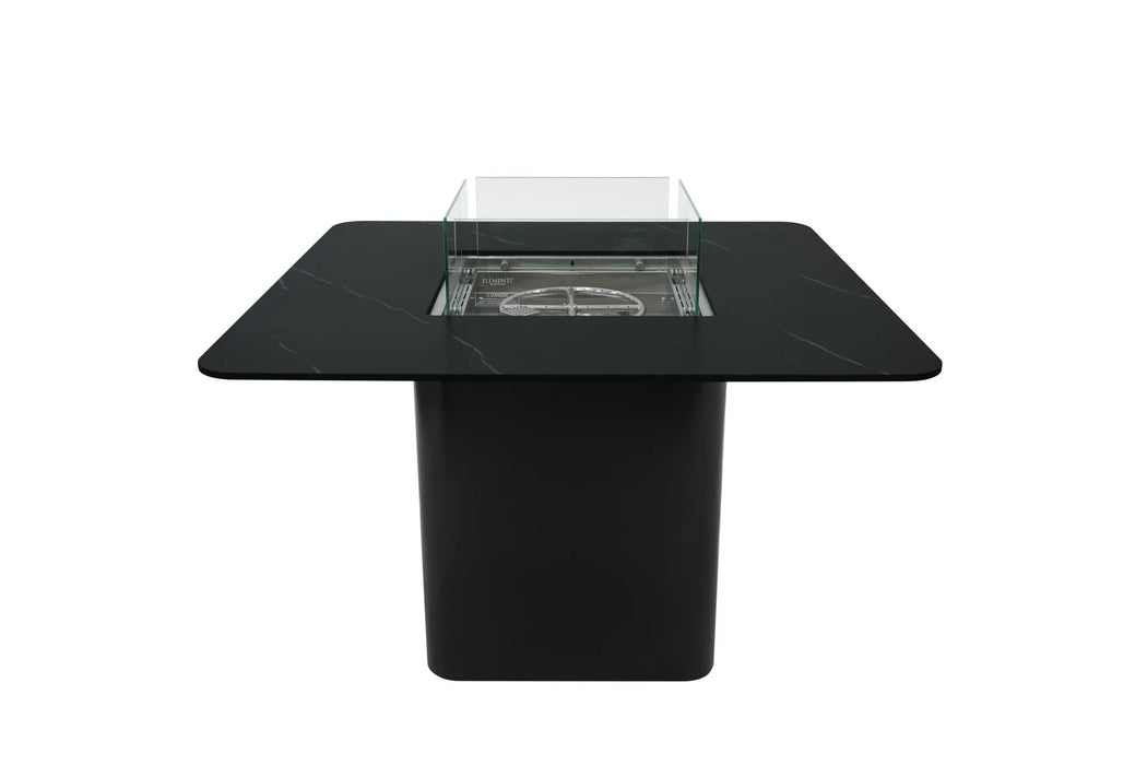  A square black fire pit table with a dark surface and a black base, featuring a rectangular fire pit in the center enclosed by a glass surround. Isolated on a white background.