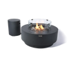 Image of a round, dark gray fire table with a glass wind guard and a separate propane tank on a checkered background.