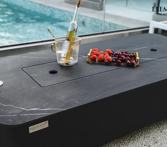 rectangular outdoor fire pit with lid. fruit platter and wine cooler on top of fire table