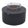 Modern, round fire pit table in dark gray with a clear glass wind guard surrounding the lava rocks and metal fasteners.