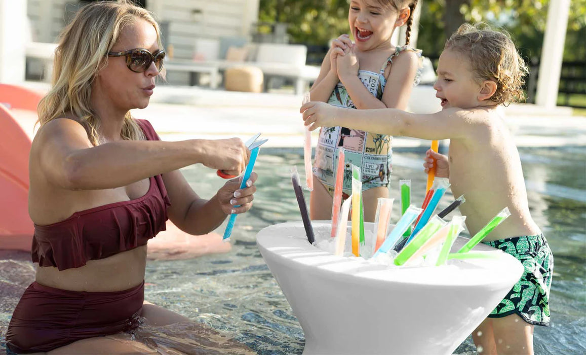 mother cutting ice lollies for children. the ice lollies are resting in a side pool table that has a built in ice bin