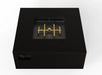 A black square gas fire pit table with a gold-colored burner inside 103816BLK