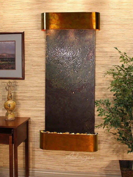 Wall-mounted water feature with bronze finish on a wall with decorative elements.