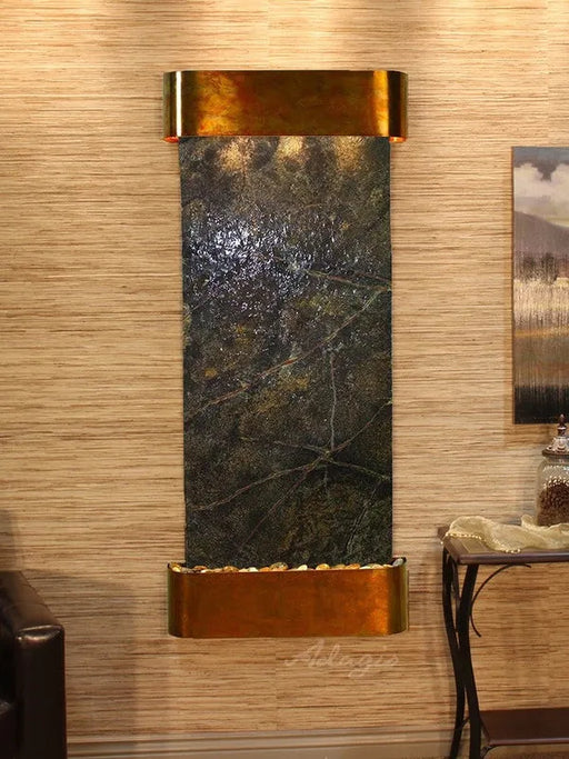 Adagio Wall-mounted water feature with bronze base and black marble-like center in a room setting.
