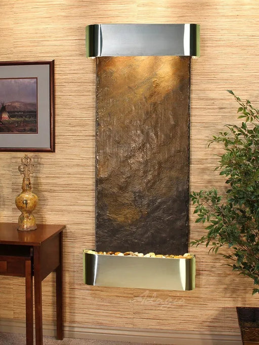 Decorative wall fountain by adagio water feature with metallic finish on a wooden wall
