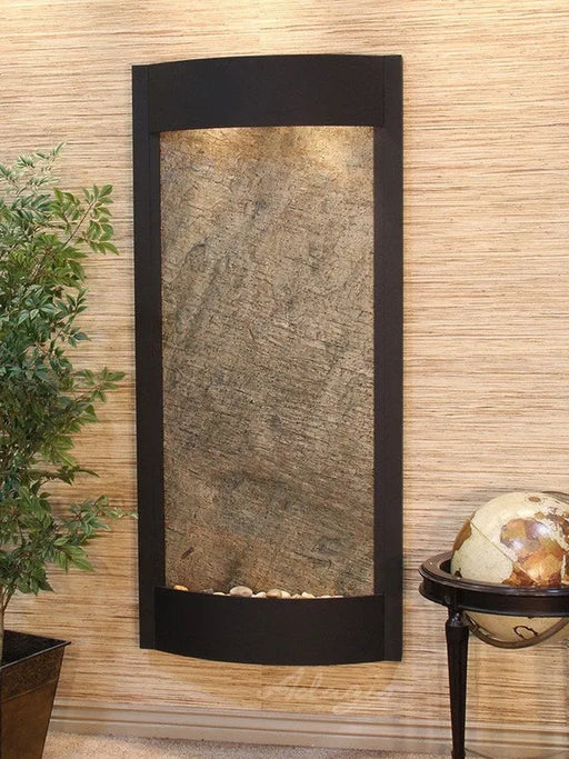 Decorative indoor wall fountain with stone-like surface and black frame on a textured wall.