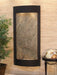 Decorative indoor wall fountain with stone-like surface and black frame on a textured wall.