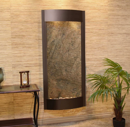 adagio wall mounted water feature with stone design in a room with a plant and small table.