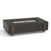 A dark gray rectangular fire table made of concrete with bronze-colored metal accents on the sides, featuring a long, rectangular stainless steel burner in the center.