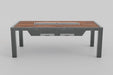 An angled front view of a bar-height outdoor grill table featuring a wood-slat top, a long built-in grill, and dark grey metal legs. A control panel with knobs is visible on the left side of the table, and two rectangular compartments are underneath.