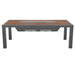 A rectangular outdoor dining table with a wood-slat top and a central built-in grill, supported by dark grey metal legs.