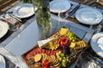 Dessert platter with fruits, cheese, and cookies on a outdoor grill table.