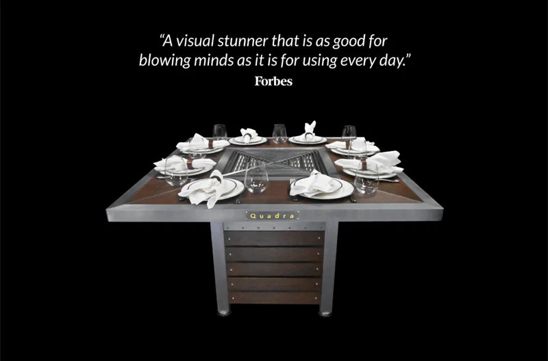 kbbq grill table table with plates and glasses, featuring the Quadra brand name, on a black background with a Forbes quote.