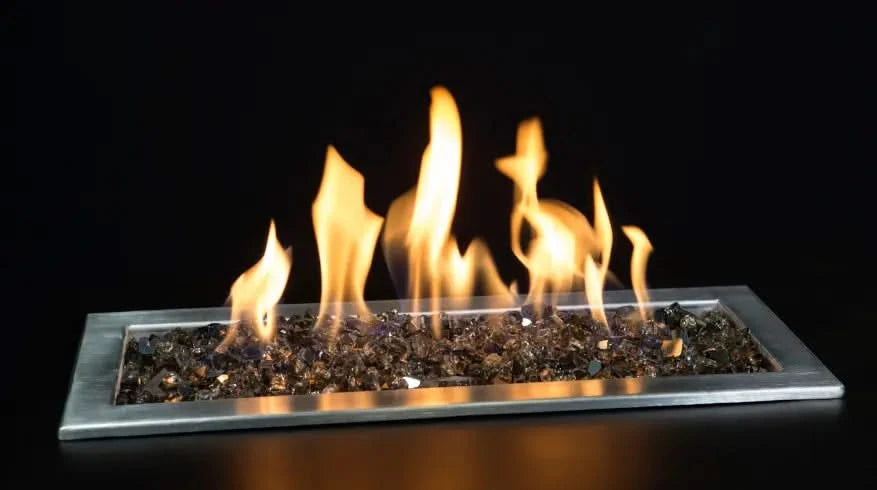 apollo bronze fire pit glass burning in fire table and blowing yellow and orange flame. fire glass is glistening on background