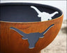 A close-up image of a wood-burning fire pit with a longhorn cutout design. The cutout is painted white against a rusty background.