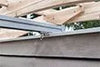 A close-up view of a silver metal track attached to a wooden pergola, designed to hold a retractable canopy.