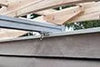 Close-up of a metal track for a retractable pergola canopy, attached to wooden beams.