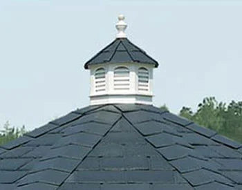 A close-up of a gazebo's bell top roof. It features a white cupola with decorative finials and ventilation louvers against a backdrop of black shingles.