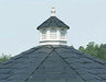 A close-up of a gazebo's bell top roof. It features a white cupola with decorative finials and ventilation louvers against a backdrop of black shingles.