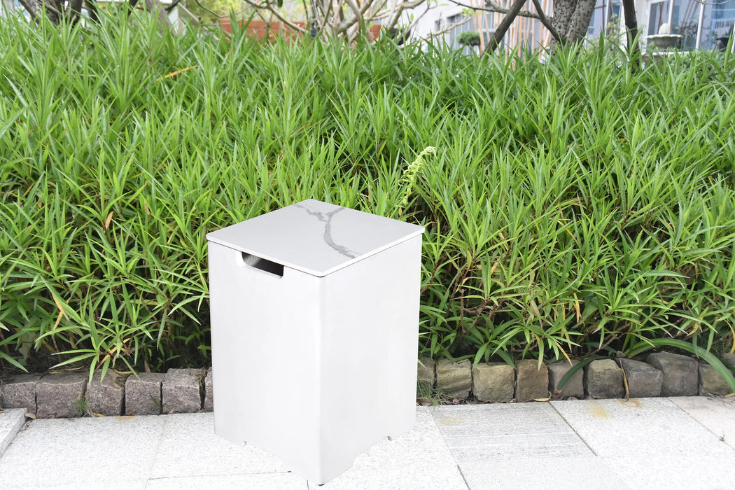 white marble square tank cover for fire pit outside in the garden in front of bushes