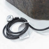 A close-up of a black gas hose connected to a silver regulator. The hose is coiled and resting on a white surface.